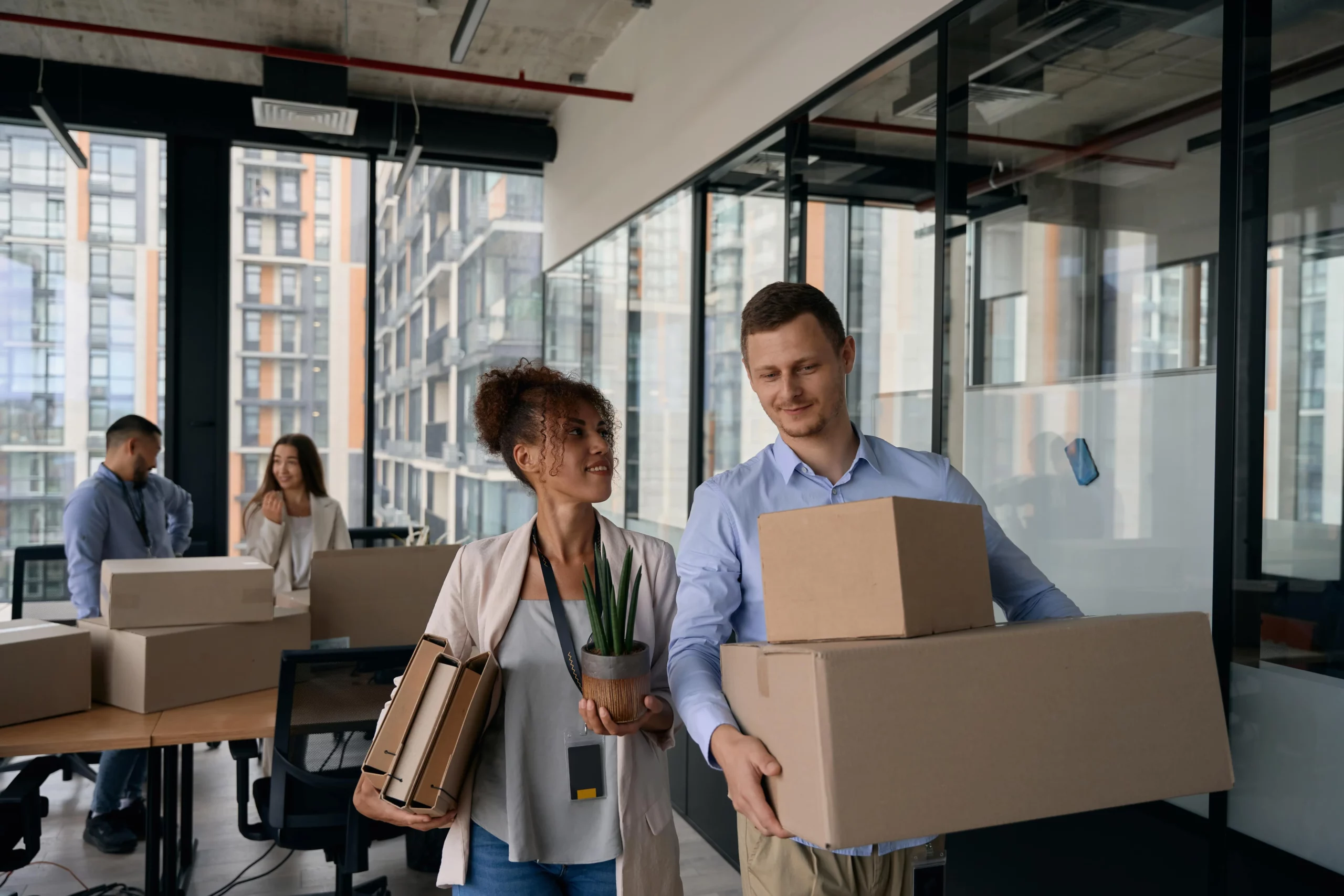 Mann und Frau tragen Umzugskartons in einem Büro für einen Firmenumzug.